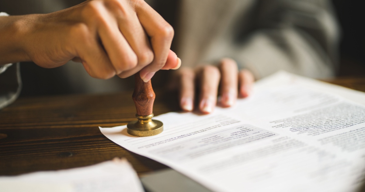 Close-up of person stamping documents to approve agreements