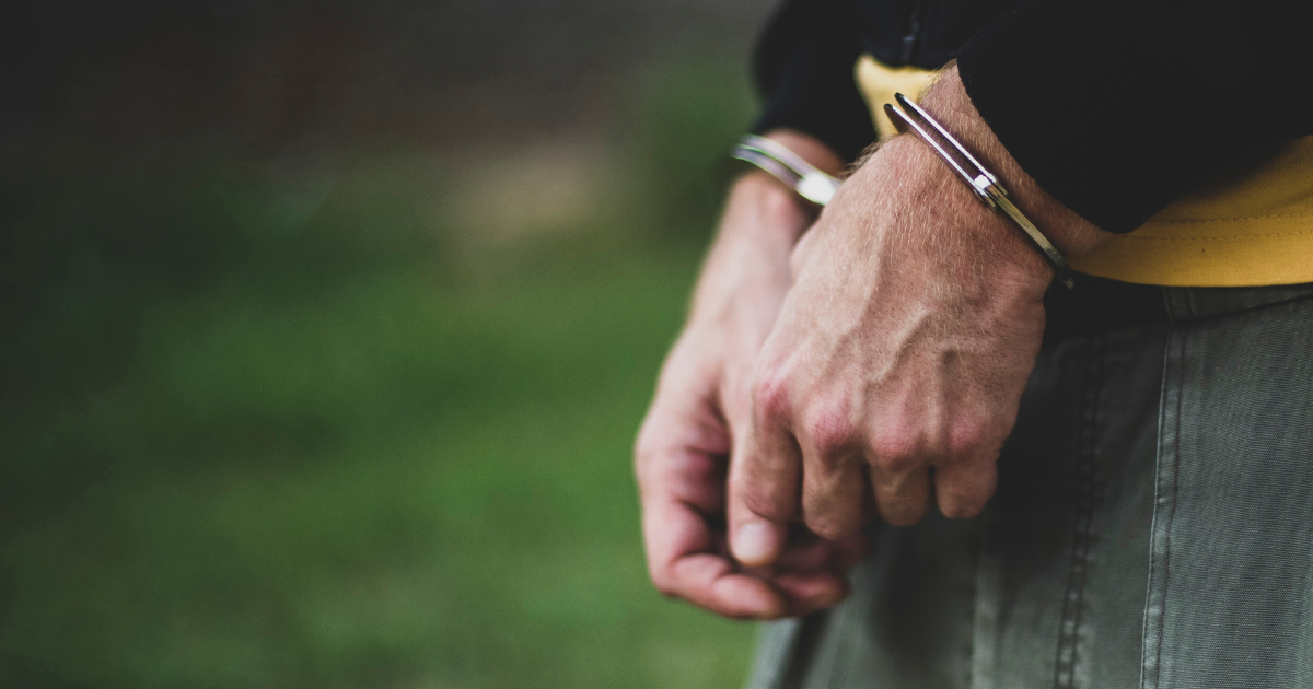 Close-up of hands in handcuffs outdoors, symbolizing law enforcement
