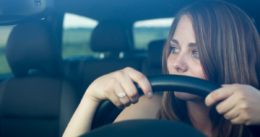 Woman sitting in a car, holding the steering wheel, with drunk reaction