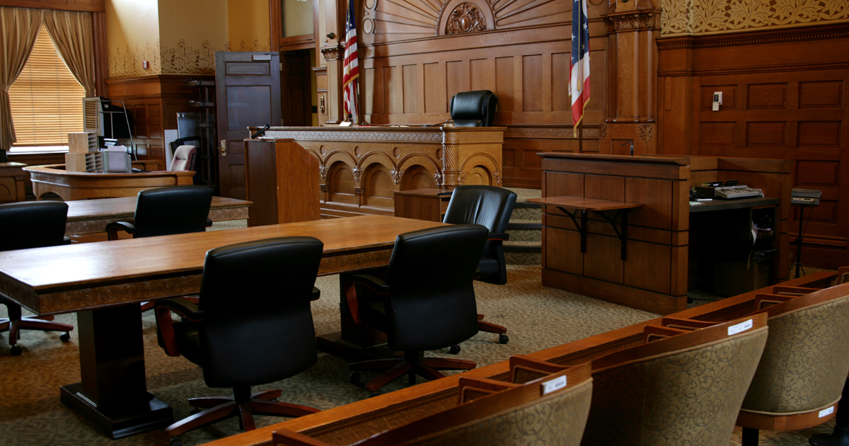 Ornate courtroom interior with wooden paneling and American flags
