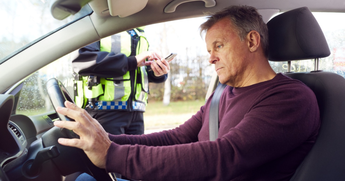 Male Driver Being Stopped By Female Traffic Police Officer With Digital Tablet For Driving Offence